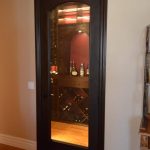 A glass-wood wine cellar door combination is not something new. It is popular though because it has this unique way of presenting what's inside a room. From this angle, you can already see the wall-mounted wine rack, red paint, and a few bottles that all look like the home is from a particular era!