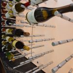 Chrome metal wine pegs look effortless against an LED backdrop inside a modern wine room.