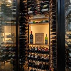 A single framed glass door serves as the main entryway into this modern wine closet.